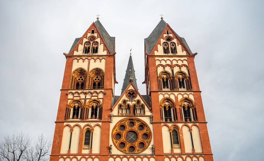 Limburg Cathedral bathed in sunlight against a backdrop of clouds